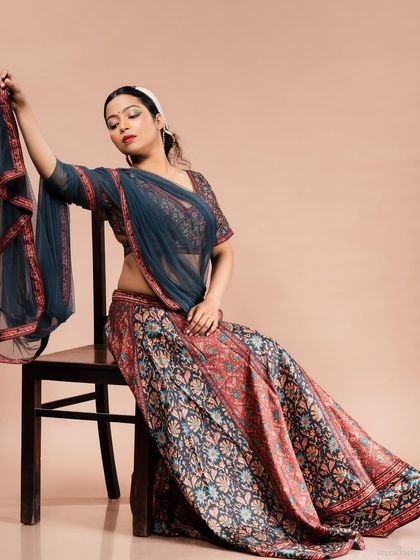 A relaxed, seated pose in the printed lehenga, showing the full outfit.