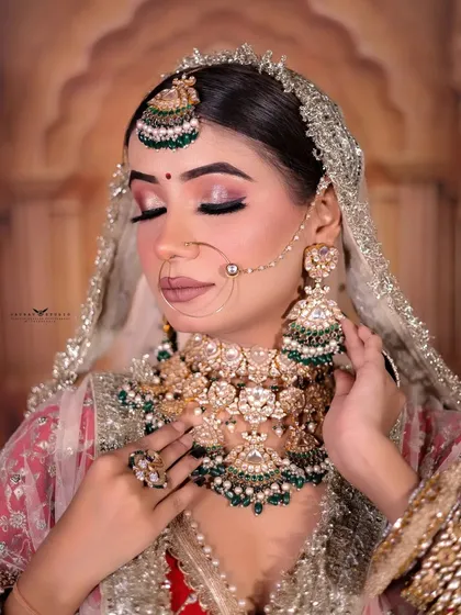 A stunning close-up with the bride's eyes closed, focusing on the detailed eye makeup and heavy bridal necklace.
