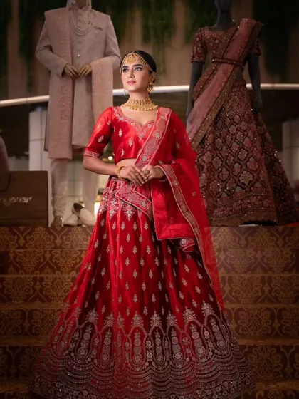 A full-length shot of the red lehenga against a backdrop of wedding collections, showing how the look fits a grand theme.