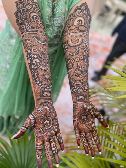 A breathtaking full-sleeve mehandi design, rich with detail. It combines peacock motifs, floral bands, and intricate fillers to create a truly royal bridal look.