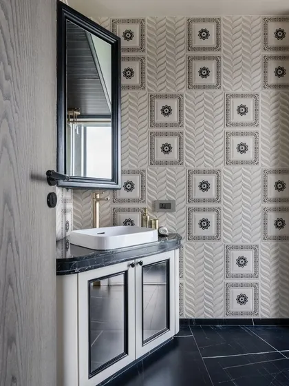 A minimalist powder room with maximum impact. The wall features a unique combination of patterned and textured tiles, while the black and white vanity adds a touch of classic elegance.