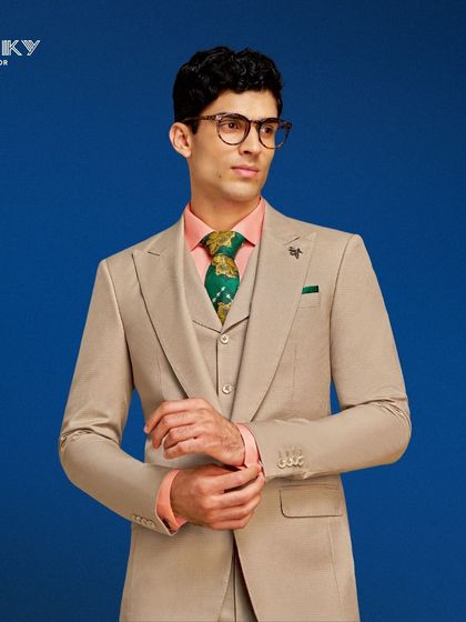 A perfectly crafted beige three-piece suit paired with a vibrant shirt and tie. This ensemble is ideal for a chic soirée or daytime event, radiating sophistication and personal style.