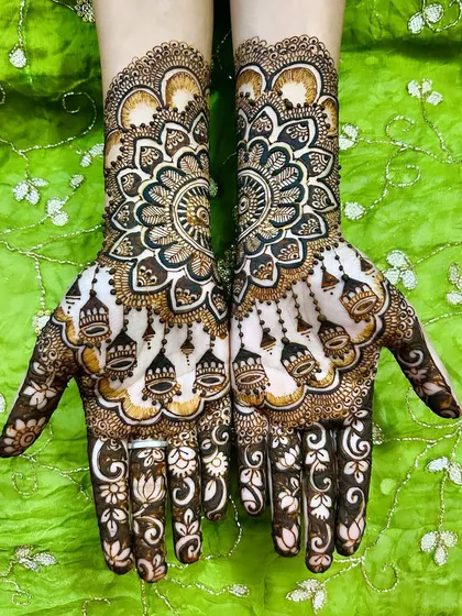 A gorgeous design featuring large mandalas on the back of the hands with hanging jhumki (bell) motifs. The fingers are adorned with delicate lotus patterns.