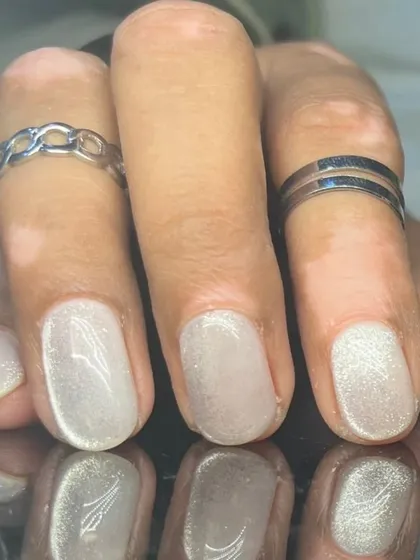 A close-up of the shimmery white cat-eye nails.