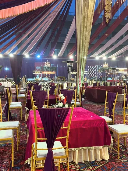 An indoor seating arrangement with a rich purple and magenta color scheme, featuring elegant chairs and a beautifully draped ceiling.