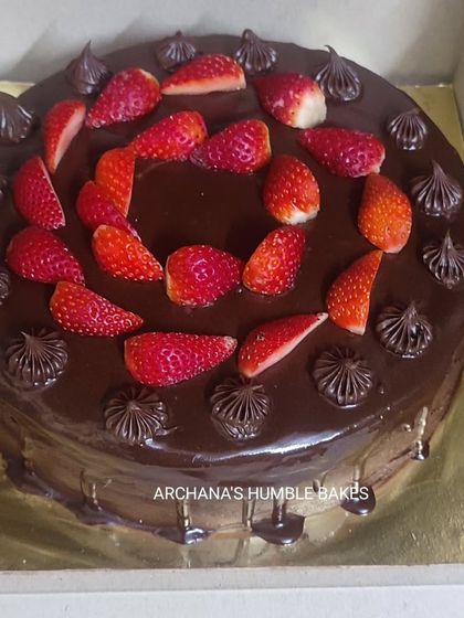A rich chocolate drip cake topped with fresh strawberries.