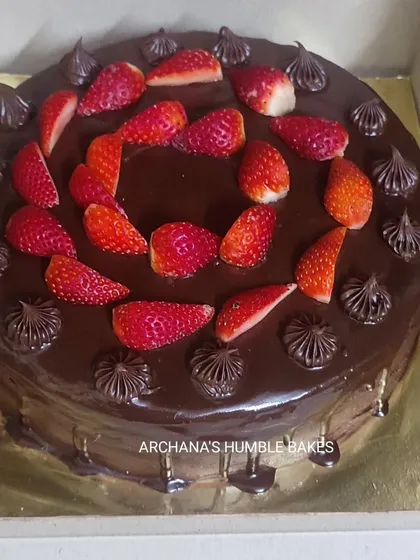 A rich chocolate drip cake topped with fresh strawberries.