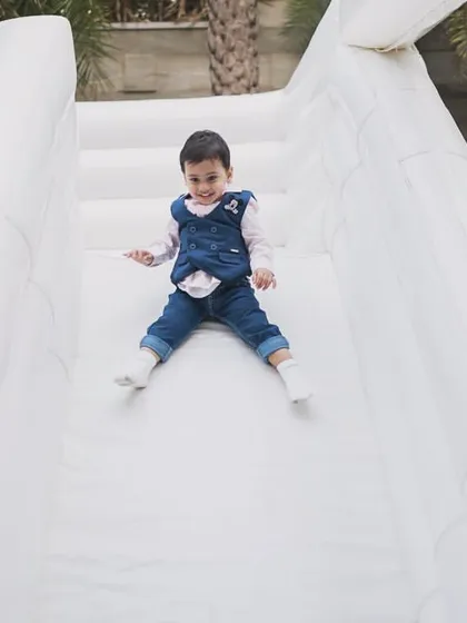 A young guest enjoying the slide on our white inflatable castle. The gentle slope is perfect for kids of all ages.