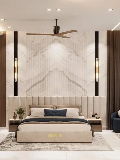 This contemporary master bedroom features fluted Statuario marble paneling and wooden louvers. The room is designed to be spacious and luxurious, with a large workstation and a comfortable seating area.