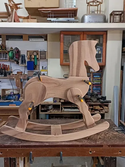 A classic rocking horse, built to be passed down through generations. This piece is mid-assembly, with the body clamped and glued, showing the solid wood construction that ensures it can handle years of play.