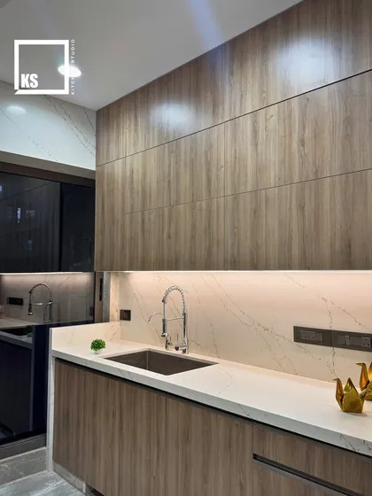 A view of the wet area, showing the seamless integration of the sink into the quartz countertop. The full-height wood-laminate panels create a cohesive and sophisticated look.