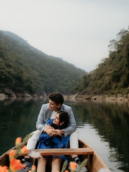 An intimate shot of a couple embracing in a boat on a serene Meghalaya lake. The perspective from within the boat creates a personal and immersive feeling for the viewer.