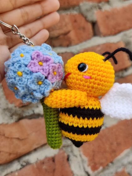 A custom-made keychain featuring a happy little bee holding a handmade hydrangea flower. The level of detail in the tiny petals was a fun challenge.