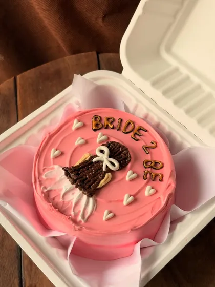 A perfect cake for a bridal shower or to celebrate a bride-to-be. This pretty pink bento cake is decorated with a drawing of a wedding dress and the words "Bride 2 Be," surrounded by tiny white hearts.