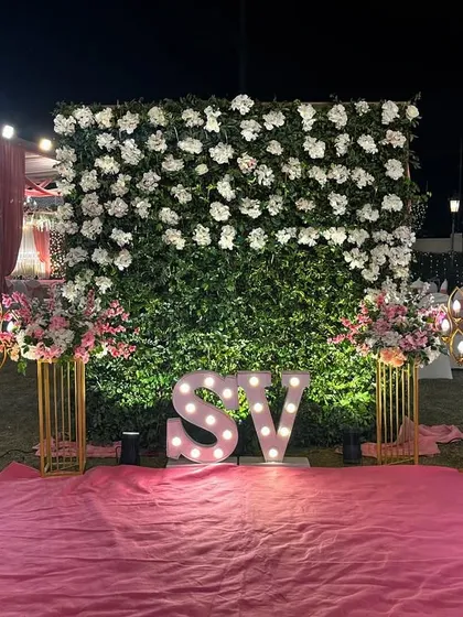 A personalized photo spot with the couple's initials in marquee lights. The backdrop is a beautiful wall of white flowers, creating an elegant and custom feature.