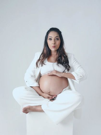 A fun and playful pose from a vogue inspired maternity shoot. The mom to be's expression adds a touch of humor and personality to this stylish portrait.