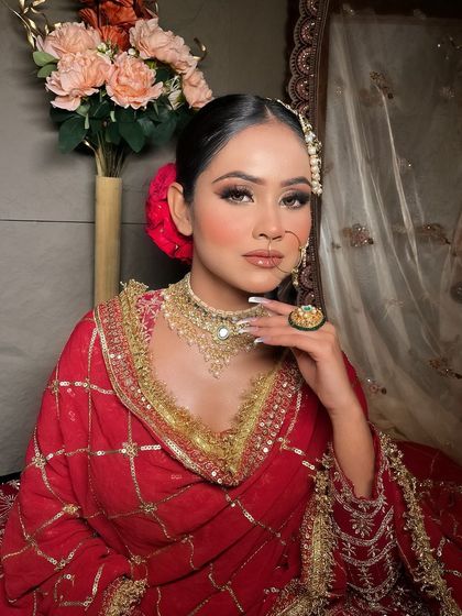 A full seated portrait of the bride in the red grid-pattern lehenga.