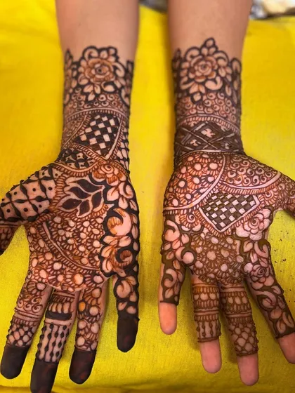 This design combines floral elements with geometric grids. The fingertips are left open, which is common in non-bridal or party mehendi.