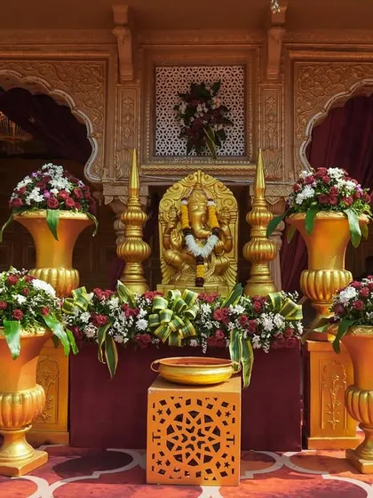 A close-up of a Ganpati idol placed at the entrance, decorated with beautiful flowers. This auspicious detail welcomes guests and blesses the occasion.