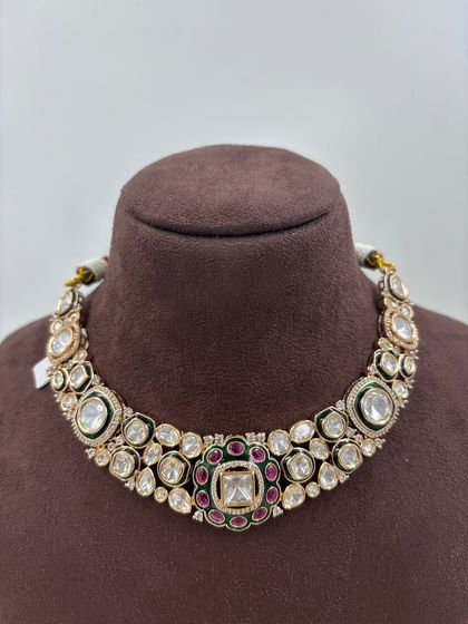 A close-up look at the fine detailing on this Moissanite and Kundan choker. The combination of large uncut stones with a ruby and emerald green center makes it a classic and highly sought-after design.
