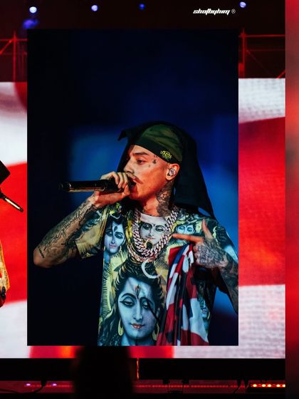 Central Cee performs at Rolling Loud India, holding the Union Jack flag while wearing his now-famous Shiva-themed t-shirt. This shot captures a culturally significant moment from his debut Indian performance.