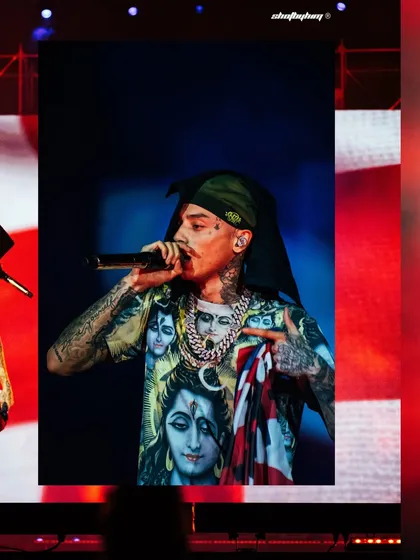 Central Cee performs at Rolling Loud India, holding the Union Jack flag while wearing his now-famous Shiva-themed t-shirt. This shot captures a culturally significant moment from his debut Indian performance.