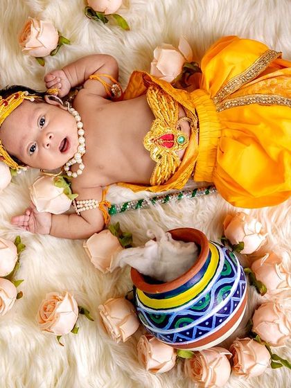 This wide shot shows the full setup for our Krishna theme, with the baby lying on a soft fur blanket surrounded by roses and his colorful matki.