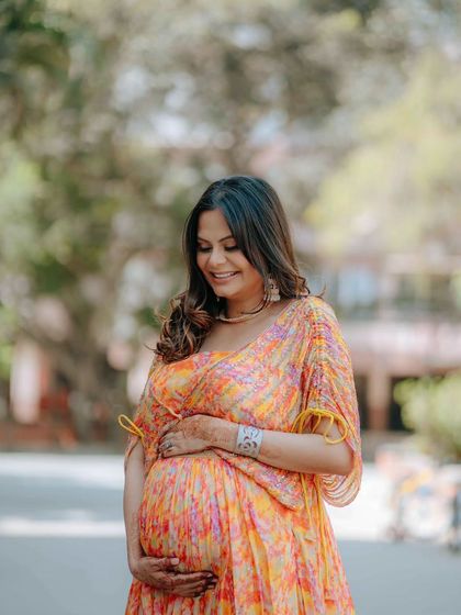 A radiant mother-to-be enjoying a moment outdoors, captured with a soft, natural light that highlights her joyful expression. This is a great example of a candid solo maternity portrait.