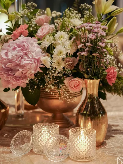 A beautiful tablescape detail from a 25th-anniversary celebration. A bouquet of pink hydrangeas and roses in a gold vase is paired with sparkling crystal votives, creating a look of pure romance.
