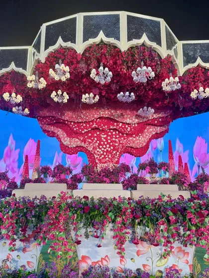 The alchemy of hues is truly unreal. This stage, with its massive floral ceiling installation and LED backdrop, is a sight for sore eyes and a testament to bold design. 🩷💜