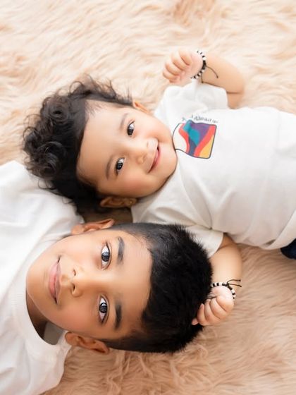 A sweet sibling portrait for Rakshabandhan, with two brothers lying side-by-side and sharing a happy moment.