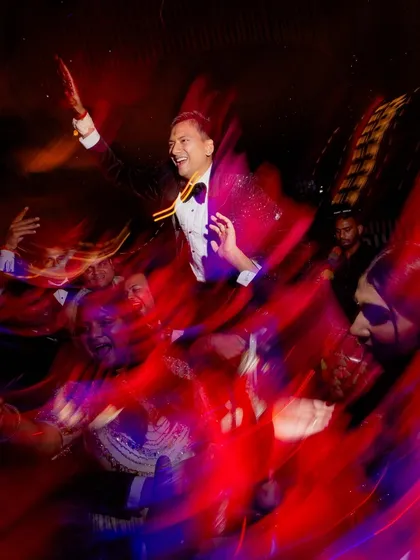 A motion-blur shot of the groom being lifted on shoulders on the dance floor. This artistic technique captures the high energy and excitement of the Sangeet party.