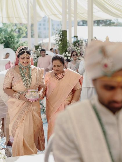 The bride's graceful entrance, escorted by her parents. The soft, neutral tones of the decor and attire create a look of timeless elegance.