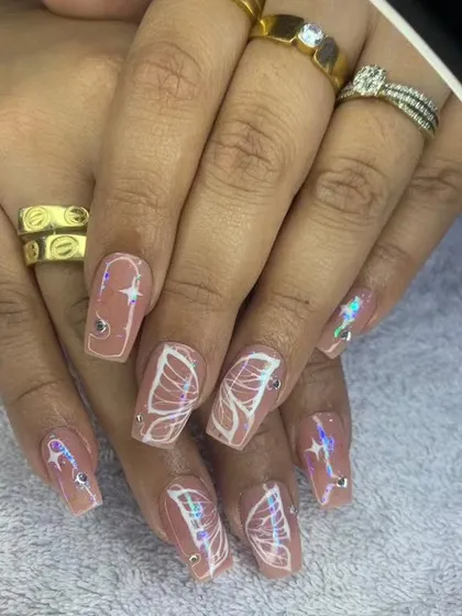 A dreamy set of square nails with a nude base, white butterfly wing outlines, and holographic star glitter.