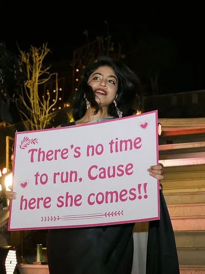 "Here she comes!" We use fun and quirky placards held by friends and family to make the bridal entry even more special.