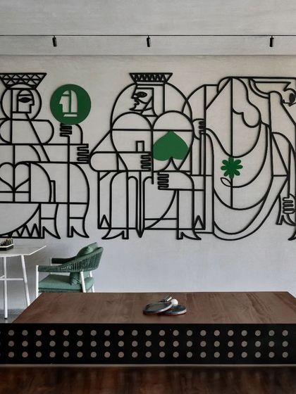 'A Queen's Gambit with the King of Spades' is a thematic wall installation made from black line metal with green accents. The piece reinterprets playing card characters into a modern, graphic artwork for a recreational space.