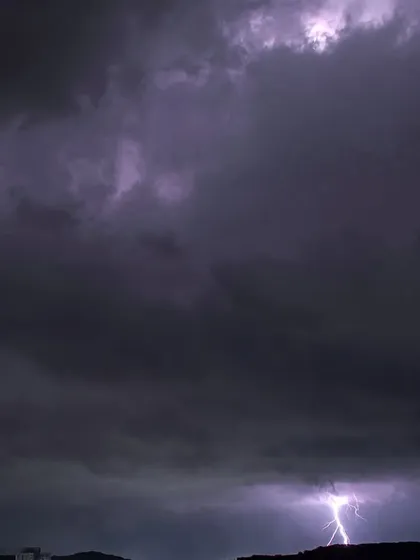 A lightning bolt strikes a distant hill in Pune, with another flash illuminating the clouds from within, creating "nature's rave."
