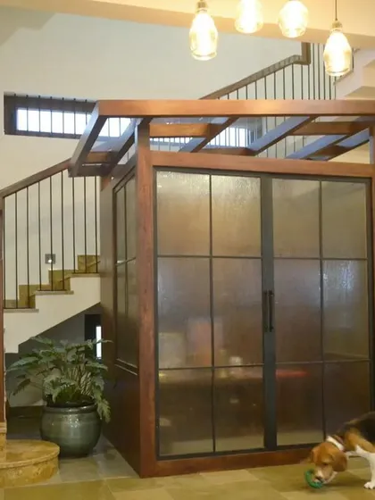 This image showcases the home's custom-built lift, seamlessly integrated next to the staircase. The wood and glass design ensures it's a beautiful feature, not just a functional necessity.