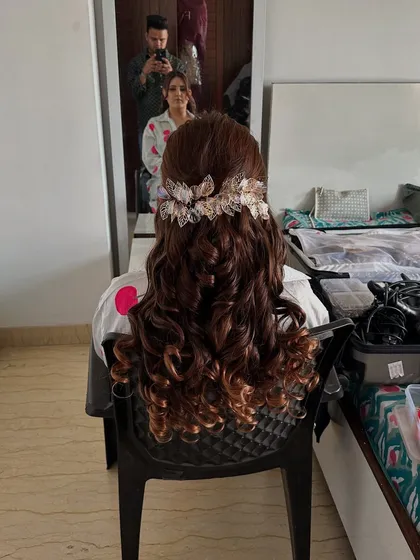 A behind-the-scenes shot of the client in the chair, showing the full length of her soft curls hairstyle.