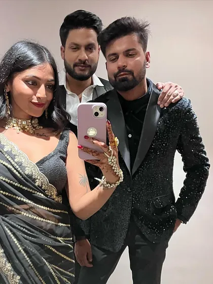 A mirror selfie with friends. My black striped saree contrasts beautifully with the sequined blazer and traditional outfits worn by others.