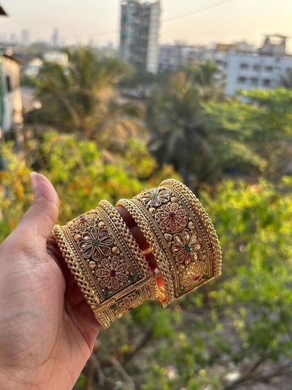 A pair of broad, intricately designed bridal bangles or 'tode'. This photo, taken in natural light, shows the beautiful floral motifs and coloured stone work.