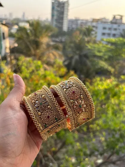 A pair of broad, intricately designed bridal bangles or 'tode'. This photo, taken in natural light, shows the beautiful floral motifs and coloured stone work.