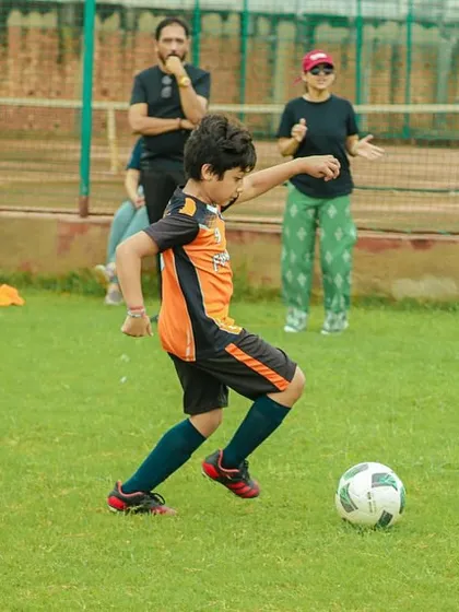 A powerful shot attempt from our player during the U8 Pride Cup, with parents watching and cheering from the sidelines.