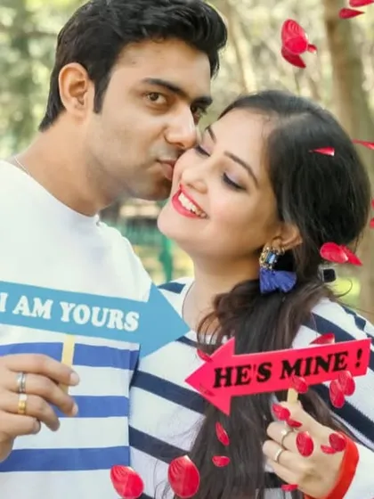 A playful and cute pre-wedding photo using "I am yours" and "He's mine" props, with falling petals adding to the romantic fun.