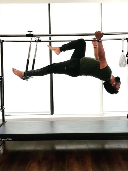 A client performs a hanging pike on the Cadillac. This is an intense core exercise that also builds upper body strength, perfect for rehabilitation and building resilience.