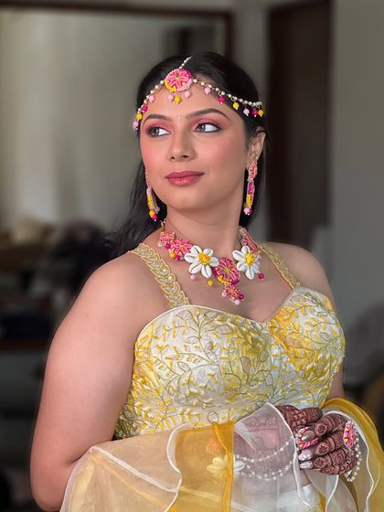 A close-up of the vibrant Haldi makeup. The artistic pink eyeliner is a perfect match for her floral jewelry, adding a fun and modern twist to the traditional look.