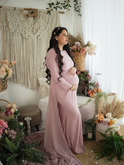 A graceful full-length portrait by the window. The soft natural light and the flowing pink gown create a dreamy and ethereal atmosphere.
