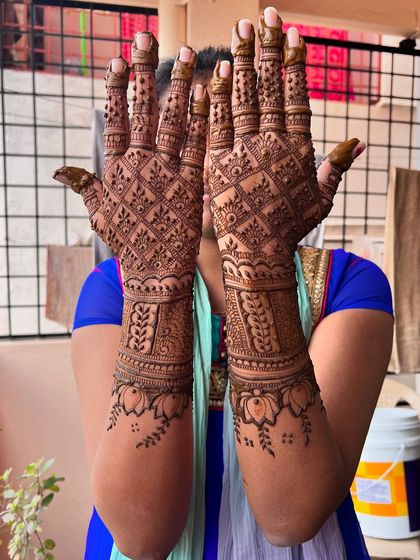 A full-coverage engagement design with a dense checkerboard pattern on the palms and lotus motifs on the arms.