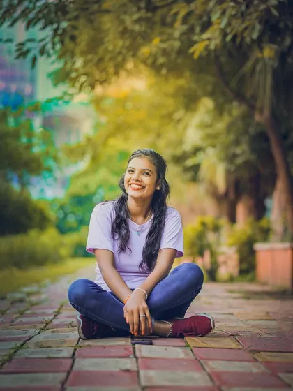 A casual outdoor portrait taken in a park. The natural light and green surroundings create a fresh and relaxed feel.