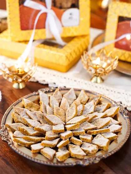 A close-up of traditional Indian sweets like Kaju Katli, specially made for dogs for Diwali. The festive, warm lighting makes the scene feel celebratory and inclusive for pets.